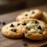 Soft and chewy homemade chocolate chip cookies with golden edges, freshly baked on a rustic wooden table.